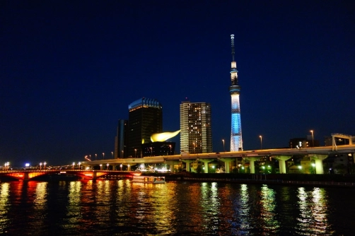 Tokyo Skytree and the Asahi Beer Hall all lit up at night next to the Sumida River (Tokyo, Japan)